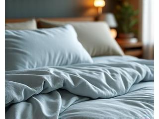 Una almohada suave y una manta sedosa en una cama bien hecha que sugiere confort y descanso.
